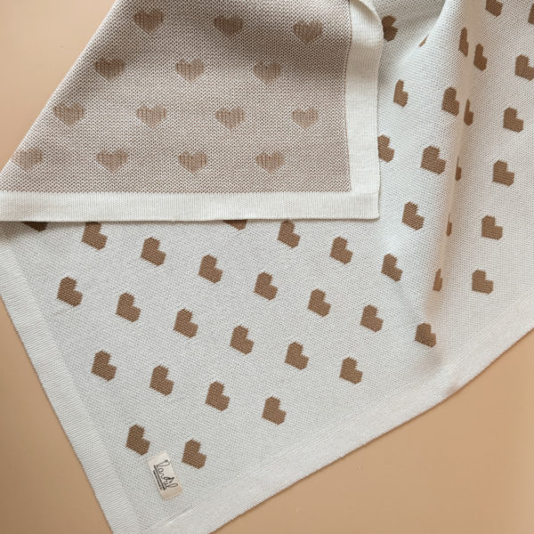 La couverture de naissance 12avril est bien plus qu’un simple accessoire : c’est un cocon de douceur et de chaleur, imaginé et tricoté avec soin en France, au cœur de la région roannaise, réputée pour son savoir-faire textile. Avec son motif all-over de petits cœurs biscuit délicatement posés sur un fond écru, elle séduit au premier regard par son esthétique tendre et intemporelle. Cette couverture est pensée pour réchauffer bébé tout en apportant une touche élégante et raffinée à sa chambre ou à vos sorties. Conçue à partir d’un fil de qualité, composé à 50% de laine, elle offre la chaleur idéale pour l’hiver tout en restant respirante. Sa texture tricotée apporte un confort douillet et une grande souplesse, parfaite pour envelopper bébé lors des siestes, des promenades ou des moments de tendresse à la maison. De forme carrée (80 x 80 cm), elle est parfaitement adaptée aux tout-petits : facile à plier, à transporter et à utiliser dans un berceau, une poussette ou un siège-auto. Elle accompagnera bébé partout, dès la naissance, en offrant une sensation rassurante de cocon et de sécurité. Chaque couverture est le fruit d’une confection locale, valorisant le savoir-faire français et une production respectueuse. C’est un cadeau de naissance idéal, qui allie esthétisme, praticité et authenticité. Offrir ou s’offrir la couverture de naissance 12avril, c’est choisir un produit de caractère, plein de tendresse, pensé pour durer et transmettre la chaleur de l’amour dès les premiers jours de vie.