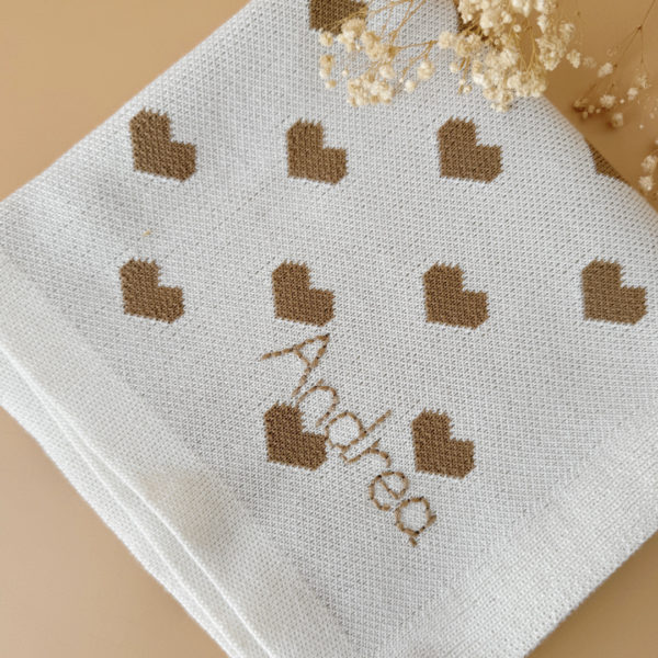 La couverture de naissance 12avril est bien plus qu’un simple accessoire : c’est un cocon de douceur et de chaleur, imaginé et tricoté avec soin en France, au cœur de la région roannaise, réputée pour son savoir-faire textile. Avec son motif all-over de petits cœurs biscuit délicatement posés sur un fond écru, elle séduit au premier regard par son esthétique tendre et intemporelle. Cette couverture est pensée pour réchauffer bébé tout en apportant une touche élégante et raffinée à sa chambre ou à vos sorties. Conçue à partir d’un fil de qualité, composé à 50% de laine, elle offre la chaleur idéale pour l’hiver tout en restant respirante. Sa texture tricotée apporte un confort douillet et une grande souplesse, parfaite pour envelopper bébé lors des siestes, des promenades ou des moments de tendresse à la maison. De forme carrée (80 x 80 cm), elle est parfaitement adaptée aux tout-petits : facile à plier, à transporter et à utiliser dans un berceau, une poussette ou un siège-auto. Elle accompagnera bébé partout, dès la naissance, en offrant une sensation rassurante de cocon et de sécurité. Chaque couverture est le fruit d’une confection locale, valorisant le savoir-faire français et une production respectueuse. C’est un cadeau de naissance idéal, qui allie esthétisme, praticité et authenticité. Offrir ou s’offrir la couverture de naissance 12avril, c’est choisir un produit de caractère, plein de tendresse, pensé pour durer et transmettre la chaleur de l’amour dès les premiers jours de vie.