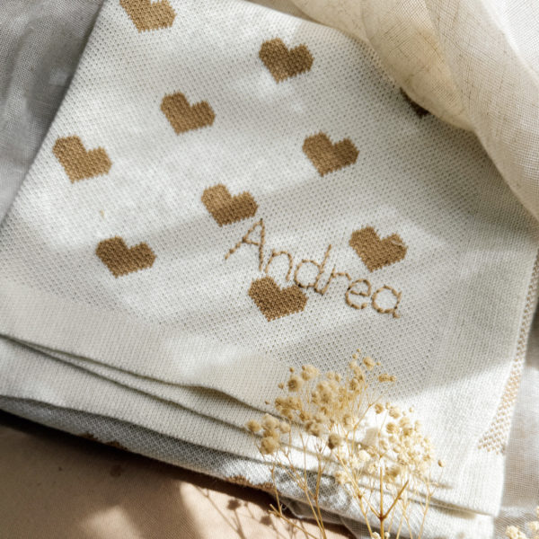 La couverture de naissance 12avril est bien plus qu’un simple accessoire : c’est un cocon de douceur et de chaleur, imaginé et tricoté avec soin en France, au cœur de la région roannaise, réputée pour son savoir-faire textile. Avec son motif all-over de petits cœurs biscuit délicatement posés sur un fond écru, elle séduit au premier regard par son esthétique tendre et intemporelle. Cette couverture est pensée pour réchauffer bébé tout en apportant une touche élégante et raffinée à sa chambre ou à vos sorties. Conçue à partir d’un fil de qualité, composé à 50% de laine, elle offre la chaleur idéale pour l’hiver tout en restant respirante. Sa texture tricotée apporte un confort douillet et une grande souplesse, parfaite pour envelopper bébé lors des siestes, des promenades ou des moments de tendresse à la maison. De forme carrée (80 x 80 cm), elle est parfaitement adaptée aux tout-petits : facile à plier, à transporter et à utiliser dans un berceau, une poussette ou un siège-auto. Elle accompagnera bébé partout, dès la naissance, en offrant une sensation rassurante de cocon et de sécurité. Chaque couverture est le fruit d’une confection locale, valorisant le savoir-faire français et une production respectueuse. C’est un cadeau de naissance idéal, qui allie esthétisme, praticité et authenticité. Offrir ou s’offrir la couverture de naissance 12avril, c’est choisir un produit de caractère, plein de tendresse, pensé pour durer et transmettre la chaleur de l’amour dès les premiers jours de vie.
