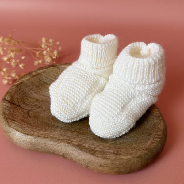 Chaussons de naissance tricoté écru 1 Les premiers jours de bébé sont précieux, et chaque détail compte pour assurer son confort et sa chaleur. Les chaussons tricotés réchaufferont les petits pieds de votre tout-petit pour ces premiers jours. Tricoté avec soin cette laine alpaga apporte de la chaleur, une légèreté, un fil chaud , doux et léger. Ils sont fabriqués dans l’un de nos ateliers partenaires français. Grâce à sa texture et à sa conception, nos chaussons de naissance maintiennent la chaleur corporelle de votre bébé au niveau de ces petits pieds.  Offrez à votre bébé le confort et la chaleur dont il a besoin  en complétant son trousseau de naissance avec le petit béguin tricoté assorti . Un cadeau parfaitement adapté pour accueillir votre petit trésor dans le monde avec tendresse et douceur. Vous pouvez également compléter ce petit look de naissance avec l’une de nos brassières douce et chaude en maille.