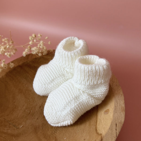 Chaussons de naissance tricoté écru 2 12avril Les premiers jours de bébé sont précieux, et chaque détail compte pour assurer son confort et sa chaleur. Les chaussons tricotés réchaufferont les petits pieds de votre tout-petit pour ces premiers jours. Tricoté avec soin cette laine alpaga apporte de la chaleur, une légèreté, un fil chaud , doux et léger. Ils sont fabriqués dans l’un de nos ateliers partenaires français. Grâce à sa texture et à sa conception, nos chaussons de naissance maintiennent la chaleur corporelle de votre bébé au niveau de ces petits pieds.  Offrez à votre bébé le confort et la chaleur dont il a besoin  en complétant son trousseau de naissance avec le petit béguin tricoté assorti . Un cadeau parfaitement adapté pour accueillir votre petit trésor dans le monde avec tendresse et douceur. Vous pouvez également compléter ce petit look de naissance avec l’une de nos brassières douce et chaude en maille.