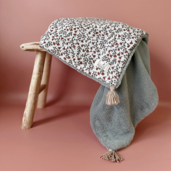 La couverture est une des pièces indispensable du trousseau de bébé. Parfaite en cadeau de naissance ou à s’offrir soit même, cette couverture chaude spéciale “bébés d’hiver”, vous accompagnera très longtemps dans vos moments câlins avec bébé. Les bébés d’hiver qui naissent pendant les mois les plus froids ont besoin d'être tenus bien au chaud à la sortie du ventre de maman. C'est pourquoi nous avons conçu cette couverture chaude spéciale “bébé d’hiver”. Dès son arrivée, bébé passe d'un environnement clos de 37°C à une température extérieure souvent très basse en hiver. C'est pour cela que nos couvertures d'hiver sont idéales pour réguler et maintenir une bonne température pour le corps de bébé.  Cette grande couverture pourra également être utilisée en descente de lit quand bébé sera plus grand. Cette couverture est idéale pour bien réchauffer les bébés d’hiver grâce à sa fausse fourrure extra douce, très épaisse (365g/m2), et sa doublure en gaze de coton hypoallergénique au magnifique motif d'un doux feuillage et de petites hirondelles. Un motif doux et unisexe. Quatre pompons en laine beige doré viennent sublimer la couverture dans les angles. Ils sont fabriqués à la main pour une pièce encore plus unique. Chaque pompon est posé très fermement avec des points solides afin de garantir une sécurité optimale pour votre enfant.