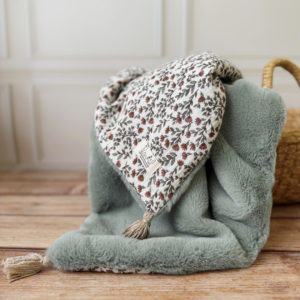 La couverture est une des pièces indispensable du trousseau de bébé. Parfaite en cadeau de naissance ou à s’offrir soit même, cette couverture chaude spéciale “bébés d’hiver”, vous accompagnera très longtemps dans vos moments câlins avec bébé. Les bébés d’hiver qui naissent pendant les mois les plus froids ont besoin d'être tenus bien au chaud à la sortie du ventre de maman. C'est pourquoi nous avons conçu cette couverture chaude spéciale “bébé d’hiver”. Dès son arrivée, bébé passe d'un environnement clos de 37°C à une température extérieure souvent très basse en hiver. C'est pour cela que nos couvertures d'hiver sont idéales pour réguler et maintenir une bonne température pour le corps de bébé.  Cette grande couverture pourra également être utilisée en descente de lit quand bébé sera plus grand. Cette couverture est idéale pour bien réchauffer les bébés d’hiver grâce à sa fausse fourrure extra douce, très épaisse (365g/m2), et sa doublure en gaze de coton hypoallergénique au magnifique motif d'un doux feuillage et de petites hirondelles. Un motif doux et unisexe. Quatre pompons en laine beige doré viennent sublimer la couverture dans les angles. Ils sont fabriqués à la main pour une pièce encore plus unique. Chaque pompon est posé très fermement avec des points solides afin de garantir une sécurité optimale pour votre enfant.