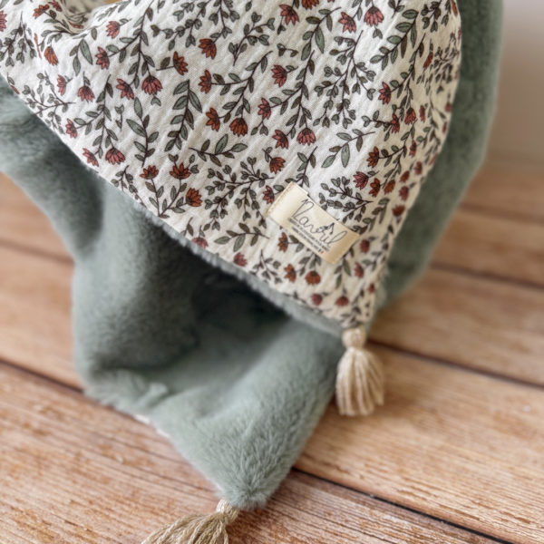 La couverture est une des pièces indispensable du trousseau de bébé. Parfaite en cadeau de naissance ou à s’offrir soit même, cette couverture chaude spéciale “bébés d’hiver”, vous accompagnera très longtemps dans vos moments câlins avec bébé. Les bébés d’hiver qui naissent pendant les mois les plus froids ont besoin d'être tenus bien au chaud à la sortie du ventre de maman. C'est pourquoi nous avons conçu cette couverture chaude spéciale “bébé d’hiver”. Dès son arrivée, bébé passe d'un environnement clos de 37°C à une température extérieure souvent très basse en hiver. C'est pour cela que nos couvertures d'hiver sont idéales pour réguler et maintenir une bonne température pour le corps de bébé.  Cette grande couverture pourra également être utilisée en descente de lit quand bébé sera plus grand. Cette couverture est idéale pour bien réchauffer les bébés d’hiver grâce à sa fausse fourrure extra douce, très épaisse (365g/m2), et sa doublure en gaze de coton hypoallergénique au magnifique motif d'un doux feuillage et de petites hirondelles. Un motif doux et unisexe. Quatre pompons en laine beige doré viennent sublimer la couverture dans les angles. Ils sont fabriqués à la main pour une pièce encore plus unique. Chaque pompon est posé très fermement avec des points solides afin de garantir une sécurité optimale pour votre enfant.