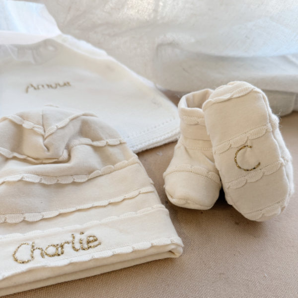 Immortaliser les premiers jours de vie de bébé avec ce joli petit bonnet personnalisé. Il est en 100% jersey de coton biologique écru. Il sera réchauffer bébé. Idéale pour annoncer le prénom de bébé à la naissance ! Le saviez-vous? Toutes les extrémités du corps de bébé sont les plus vulnérables au froid , pieds, mains, oreilles ... Même en plein été il est important de bien couvrir bébé dès la naissance, n'oublions pas qu'il sort d'un bain de 37° C depuis 9 mois ! Le petit plus: la broderie qui annonce le prénom de bébé lui donne un côté unique ! La broderie est réalisée à la main. Elle est constituée du prénom ou du mot . Dimension : Taille naissance / 1 mois Conseil d’entretien : Lavage à FROID, uniquement en machine ou à la main.  Délais : 8/10 jours ouvrés - Tous nos produits sont fabriqués en France.