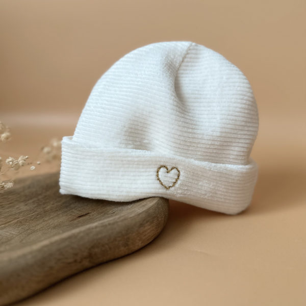 Le bonnet de naissance personnalisé pour bébé en maille velours côtelée est l'accessoire idéal pour les premiers jours de votre nouveau-né. Confectionné avec soin dans une maille éponge côtelée , ce bonnet offre à votre bébé douceur et confort incomparables. Il est fabriqué dans l’un de nos ateliers partenaires français. Un cadeau parfaitement adapté pour accueillir votre petit trésor dans le monde avec tendresse et douceur. Retrouvez dans la même gamme, nos petits chaussons de naissance. Grâce à sa texture et à sa conception, ce bonnet maintient la chaleur corporelle de votre bébé, de sorte que celui-ci sera bien au chaud pendant ses premiers jours. Ce bonnet peut être personnalisé avec l'initiale de bébé entouré d'un petit coeur ou bien d'un petit coeur vide, ce qui en fait un cadeau unique et attentionné. Offrez à votre bébé le confort et la chaleur dont il a besoin avec ce bonnet de naissance personnalisé en maille éponge côtelée. Un cadeau parfaitement adapté pour accueillir votre petit trésor dans le monde avec tendresse et douceur. Son design simple et élégant s'accorde facilement avec toutes les tenues de bébé, notamment à notre douce brassière de naissance ajourée écrue.