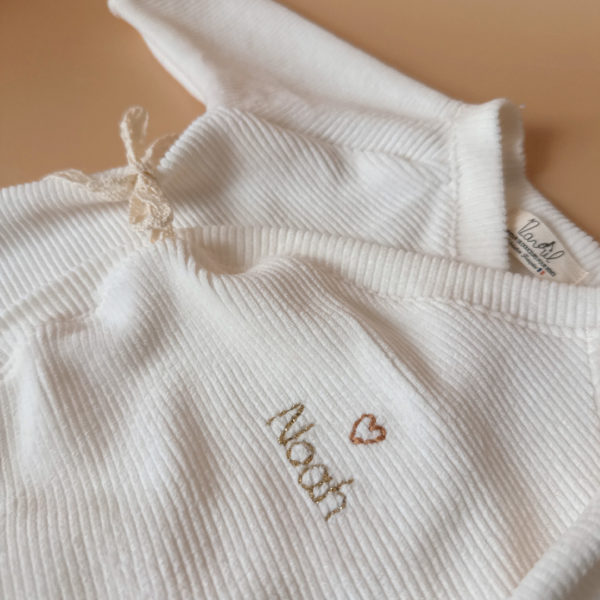 Offrez à votre nouveau-né un confort absolu avec notre pyjama de naissance écru en mini maille côtelée, soigneusement fabriqué en France. Ce pyjama allie douceur et praticité, idéal pour les premiers mois de bébé. Son design élégant en maille de velours côtelé offre une texture agréable au toucher, tandis que sa teinte écrue apporte une touche intemporelle. Il se distingue par sa personnalisation au prénom de votre enfant, en faisant un cadeau unique et inoubliable. Pratique, il est doté d'une fermeture sur le devant pour faciliter l'habillage, ainsi qu'une ouverture intégrale au niveau des pieds, rendant le changement de couches simple et rapide. Un incontournable pour le trousseau de naissance, conçu pour offrir à votre bébé le meilleur dès ses premiers jours. Un cadeau parfaitement adapté pour accueillir votre petit trésor dans le monde avec tendresse et douceur. Retrouvez dans la même gamme, nos petits chaussons de naissance ainsi que nos bonnets.
