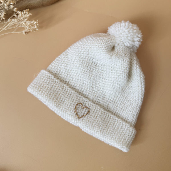 e bonnet de naissance personnalisé pour bébé en maille tricotée de coton est l'accessoire idéal pour les premiers jours de votre nouveau-né. Confectionné avec soin, ce bonnet offre à votre bébé douceur et confort incomparables. Il est fabriqué dans l’un de nos ateliers partenaires français. Un cadeau parfaitement adapté pour accueillir votre petit trésor dans le monde avec tendresse et douceur. Retrouvez dans la même gamme, nos petits chaussons de naissance. Grâce à sa texture et à sa conception, ce bonnet maintient la chaleur corporelle de votre bébé, de sorte que celui-ci sera bien au chaud pendant ses premiers jours.  Extra chaud, il est tricoté à la main dans une laine spéciale layette 100% laine mérinos. 