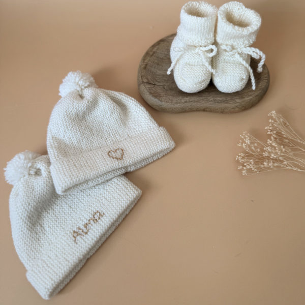 Le bonnet de naissance personnalisé pour bébé en maille tricotée de coton est l'accessoire idéal pour les premiers jours de votre nouveau-né. Confectionné avec soin, ce bonnet offre à votre bébé douceur et confort incomparables. Il est fabriqué dans l’un de nos ateliers partenaires français. Un cadeau parfaitement adapté pour accueillir votre petit trésor dans le monde avec tendresse et douceur. Retrouvez dans la même gamme, nos petits chaussons de naissance. Grâce à sa texture et à sa conception, ce bonnet maintient la chaleur corporelle de votre bébé, de sorte que celui-ci sera bien au chaud pendant ses premiers jours.  Extra chaud, il est tricoté à la main dans une laine spéciale layette 100% laine mérinos. 
