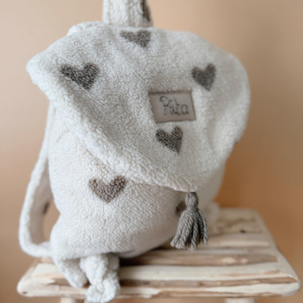 Adoptez notre tout nouveau sac à dos, il est idéal pour emporter le change, le biberon, la gourde, le départ pour la crèche, la nounou mais aussi les premiers pas pour l'école ! Il est tout doux, tout mou et tout léger pour prendre soin du dos de votre enfant. Il est réalisé en fausse fourrure sherpa,  ouatiné , dans nos ateliers français. Notre emblématique pompon vient habillé le petit rabat qui est lui même muni d'une pression. Les anses sont ajustables en réglant les petits nœuds. Fabriqué en sherpa  tout doux, il assure le confort de votre bébé tout en étant doux et léger au porter;. Doté de bretelles réglables et d'une poignée de transport pratique, ce sac à dos est parfaitement adapté à la morphologie de votre enfant et offre une grande facilité d'utilisation. Idéal pour les sorties en famille, les promenades au parc ou les voyages, ce sac à dos offre suffisamment d'espace pour ranger les essentiels de bébé tout en restant léger et compact.
