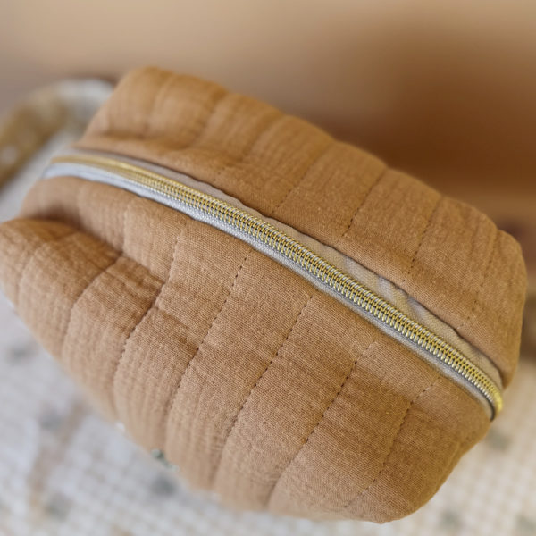 La trousse de toilette pour bébé est une pièce personnalisée et pratique, conçue avec soin pour répondre aux besoins des parents et de leur nouveau-né. Vous serez conquis par son grand format. La conception de la trousse permet aux produits de bébé de tenir debout à l'intérieur, ce qui facilite l'organisation et l'accès aux produits essentiels. Liniment, couches, lait de toilette, cotons, autant de produits pour un si petit bout de chou, que vous aurez besoin d'une grande trousse de toilette spacieuse. Fabriquée en gaze de coton matelassée, cette trousse est à la fois douce et durable. L'intérieur de la trousse est doublé avec un tissu imperméable. Les liquides renversés ne pénètrent pas à l'extérieur, protégeant ainsi les autres articles dans le sac. Personnaliser votre trousse de toilette, au doux prénom de bébé ! La personnalisation est réalisée à la main sur le devant de la trousse de toilette. Fièrement fabriquée en France, cette trousse de toilette est le fruit d'un savoir-faire artisanal et d'une attention particulière aux détails. Zoom sur le petit curseur de la fermeture à glissière ! Découvrez notre gamme entière de produits de ce thème: langes, couvertures, doudous lange...