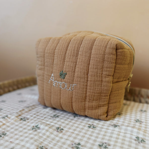 La trousse de toilette pour bébé est une pièce personnalisée et pratique, conçue avec soin pour répondre aux besoins des parents et de leur nouveau-né. Vous serez conquis par son grand format. La conception de la trousse permet aux produits de bébé de tenir debout à l'intérieur, ce qui facilite l'organisation et l'accès aux produits essentiels. Liniment, couches, lait de toilette, cotons, autant de produits pour un si petit bout de chou, que vous aurez besoin d'une grande trousse de toilette spacieuse. Fabriquée en gaze de coton matelassée, cette trousse est à la fois douce et durable. L'intérieur de la trousse est doublé avec un tissu imperméable. Les liquides renversés ne pénètrent pas à l'extérieur, protégeant ainsi les autres articles dans le sac. Personnaliser votre trousse de toilette, au doux prénom de bébé ! La personnalisation est réalisée à la main sur le devant de la trousse de toilette. Fièrement fabriquée en France, cette trousse de toilette est le fruit d'un savoir-faire artisanal et d'une attention particulière aux détails. Zoom sur le petit curseur de la fermeture à glissière ! Découvrez notre gamme entière de produits de ce thème: langes, couvertures, doudous lange...