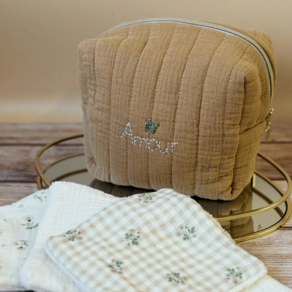 La trousse de toilette pour bébé est une pièce personnalisée et pratique, conçue avec soin pour répondre aux besoins des parents et de leur nouveau-né. Vous serez conquis par son grand format. La conception de la trousse permet aux produits de bébé de tenir debout à l'intérieur, ce qui facilite l'organisation et l'accès aux produits essentiels. Liniment, couches, lait de toilette, cotons, autant de produits pour un si petit bout de chou, que vous aurez besoin d'une grande trousse de toilette spacieuse. Fabriquée en gaze de coton matelassée, cette trousse est à la fois douce et durable. L'intérieur de la trousse est doublé avec un tissu imperméable. Les liquides renversés ne pénètrent pas à l'extérieur, protégeant ainsi les autres articles dans le sac. Personnaliser votre trousse de toilette, au doux prénom de bébé ! La personnalisation est réalisée à la main sur le devant de la trousse de toilette. Fièrement fabriquée en France, cette trousse de toilette est le fruit d'un savoir-faire artisanal et d'une attention particulière aux détails. Zoom sur le petit curseur de la fermeture à glissière ! Découvrez notre gamme entière de produits de ce thème: langes, couvertures, doudous lange...