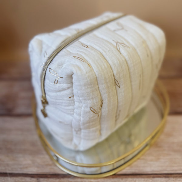 La trousse de toilette pour bébé est une pièce personnalisée et pratique, conçue avec soin pour répondre aux besoins des parents et de leur nouveau-né. Vous serez conquis par son grand format. La conception de la trousse permet aux produits de bébé de tenir debout à l'intérieur, ce qui facilite l'organisation et l'accès aux produits essentiels. Liniment, couches, lait de toilette, cotons, autant de produits pour un si petit bout de chou, que vous aurez besoin d'une grande trousse de toilette spacieuse. Fabriquée en gaze de coton matelassée, cette trousse est à la fois douce et durable. L'intérieur de la trousse est doublé avec un tissu imperméable. Les liquides renversés ne pénètrent pas à l'extérieur, protégeant ainsi les autres articles dans le sac. Personnaliser votre trousse de toilette, au doux prénom de bébé ! La personnalisation est réalisée à la main sur le devant de la trousse de toilette. Fièrement fabriquée en France, cette trousse de toilette est le fruit d'un savoir-faire artisanal et d'une attention particulière aux détails. Zoom sur le petit curseur de la fermeture à glissière ! Découvrez notre gamme entière de produits de ce thème: langes, couvertures, doudous lange...