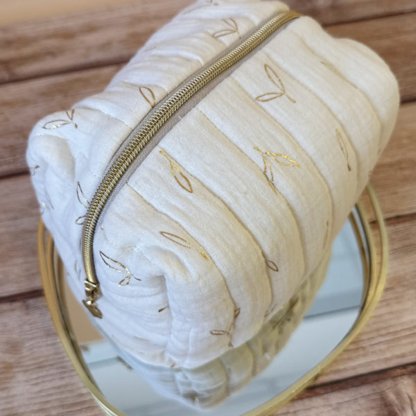 La trousse de toilette pour bébé est une pièce personnalisée et pratique, conçue avec soin pour répondre aux besoins des parents et de leur nouveau-né. Vous serez conquis par son grand format. La conception de la trousse permet aux produits de bébé de tenir debout à l'intérieur, ce qui facilite l'organisation et l'accès aux produits essentiels. Liniment, couches, lait de toilette, cotons, autant de produits pour un si petit bout de chou, que vous aurez besoin d'une grande trousse de toilette spacieuse. Fabriquée en gaze de coton matelassée, cette trousse est à la fois douce et durable. L'intérieur de la trousse est doublé avec un tissu imperméable. Les liquides renversés ne pénètrent pas à l'extérieur, protégeant ainsi les autres articles dans le sac. Personnaliser votre trousse de toilette, au doux prénom de bébé ! La personnalisation est réalisée à la main sur le devant de la trousse de toilette. Fièrement fabriquée en France, cette trousse de toilette est le fruit d'un savoir-faire artisanal et d'une attention particulière aux détails. Zoom sur le petit curseur de la fermeture à glissière ! Découvrez notre gamme entière de produits de ce thème: langes, couvertures, doudous lange...