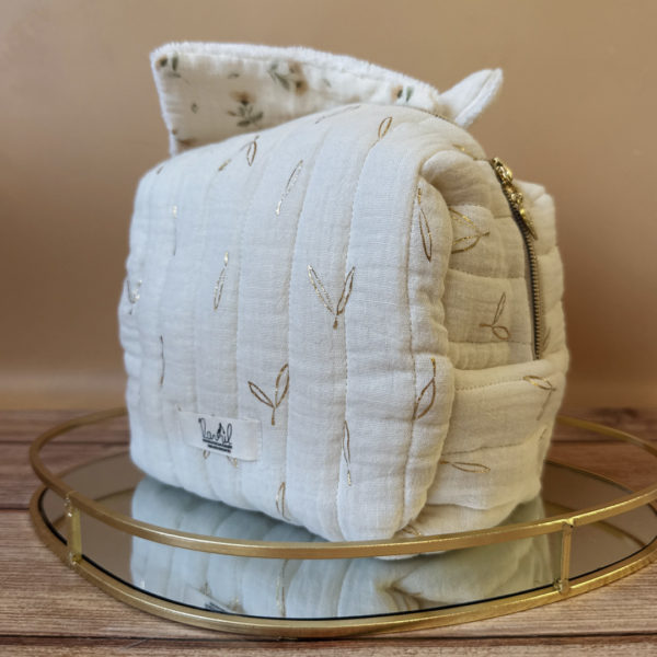 La trousse de toilette pour bébé est une pièce personnalisée et pratique, conçue avec soin pour répondre aux besoins des parents et de leur nouveau-né. Vous serez conquis par son grand format. La conception de la trousse permet aux produits de bébé de tenir debout à l'intérieur, ce qui facilite l'organisation et l'accès aux produits essentiels. Liniment, couches, lait de toilette, cotons, autant de produits pour un si petit bout de chou, que vous aurez besoin d'une grande trousse de toilette spacieuse. Fabriquée en gaze de coton matelassée, cette trousse est à la fois douce et durable. L'intérieur de la trousse est doublé avec un tissu imperméable. Les liquides renversés ne pénètrent pas à l'extérieur, protégeant ainsi les autres articles dans le sac. Personnaliser votre trousse de toilette, au doux prénom de bébé ! La personnalisation est réalisée à la main sur le devant de la trousse de toilette. Fièrement fabriquée en France, cette trousse de toilette est le fruit d'un savoir-faire artisanal et d'une attention particulière aux détails. Zoom sur le petit curseur de la fermeture à glissière ! Découvrez notre gamme entière de produits de ce thème: langes, couvertures, doudous lange...