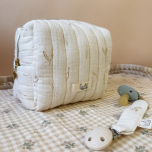 La trousse de toilette pour bébé est une pièce personnalisée et pratique, conçue avec soin pour répondre aux besoins des parents et de leur nouveau-né. Vous serez conquis par son grand format. La conception de la trousse permet aux produits de bébé de tenir debout à l'intérieur, ce qui facilite l'organisation et l'accès aux produits essentiels. Liniment, couches, lait de toilette, cotons, autant de produits pour un si petit bout de chou, que vous aurez besoin d'une grande trousse de toilette spacieuse. Fabriquée en gaze de coton matelassée, cette trousse est à la fois douce et durable. L'intérieur de la trousse est doublé avec un tissu imperméable. Les liquides renversés ne pénètrent pas à l'extérieur, protégeant ainsi les autres articles dans le sac. Personnaliser votre trousse de toilette, au doux prénom de bébé ! La personnalisation est réalisée à la main sur le devant de la trousse de toilette. Fièrement fabriquée en France, cette trousse de toilette est le fruit d'un savoir-faire artisanal et d'une attention particulière aux détails. Zoom sur le petit curseur de la fermeture à glissière ! Découvrez notre gamme entière de produits de ce thème: langes, couvertures, doudous lange...