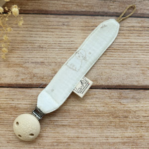 Élégante, douce et sécurisée, notre attache tétine en gaze de coton  accompagne bébé au quotidien tout en ajoutant une touche délicate à sa tenue. Chaque modèle est personnalisable avec le prénom de bébé, soigneusement brodé à la main, pour créer un accessoire unique et plein de sens. Dotée d’un lien doré raffiné pour fixer la tétine et d’une pince ronde en silicone embossé, elle allie esthétique et praticité.