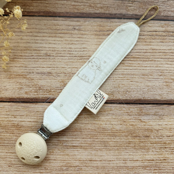 Élégante, douce et sécurisée, notre attache tétine en gaze de coton  accompagne bébé au quotidien tout en ajoutant une touche délicate à sa tenue. Chaque modèle est personnalisable avec le prénom de bébé, soigneusement brodé à la main, pour créer un accessoire unique et plein de sens. Dotée d’un lien doré raffiné pour fixer la tétine et d’une pince ronde en silicone embossé, elle allie esthétique et praticité.