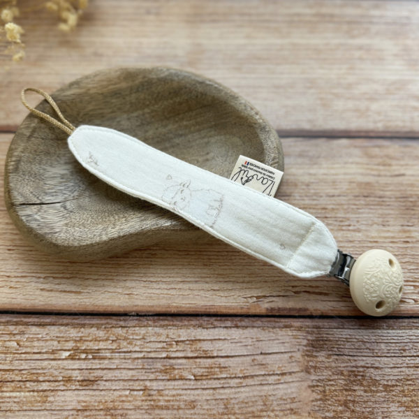Élégante, douce et sécurisée, notre attache tétine en gaze de coton  accompagne bébé au quotidien tout en ajoutant une touche délicate à sa tenue. Chaque modèle est personnalisable avec le prénom de bébé, soigneusement brodé à la main, pour créer un accessoire unique et plein de sens. Dotée d’un lien doré raffiné pour fixer la tétine et d’une pince ronde en silicone embossé, elle allie esthétique et praticité.