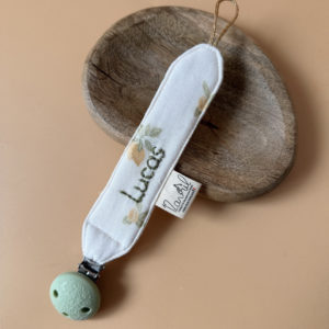 Élégante, douce et sécurisée, notre attache tétine en gaze de coton  accompagne bébé au quotidien tout en ajoutant une touche délicate à sa tenue. Chaque modèle est personnalisable avec le prénom de bébé, soigneusement brodé à la main, pour créer un accessoire unique et plein de sens. Dotée d’un lien doré raffiné pour fixer la tétine et d’une pince ronde en silicone embossé, elle allie esthétique et praticité.