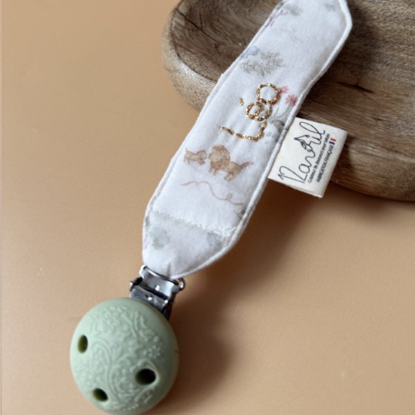 Élégante, douce et sécurisée, notre attache tétine en gaze de coton  accompagne bébé au quotidien tout en ajoutant une touche délicate à sa tenue. Chaque modèle est personnalisable avec le prénom de bébé, soigneusement brodé à la main, pour créer un accessoire unique et plein de sens. Dotée d’un lien doré raffiné pour fixer la tétine et d’une pince ronde en silicone embossé, elle allie esthétique et praticité.