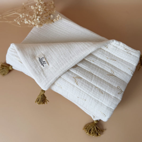 Découvrez la couverture idéale pour accompagner votre bébé pendant les beaux jours. Confectionnée en gaze de coton écrue et en gaze de coton matelassée aux délicats motifs feuillage doré, cette couverture allie douceur, légèreté et élégance.