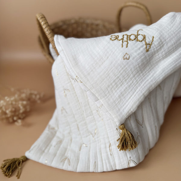 Découvrez la couverture idéale pour accompagner votre bébé pendant les beaux jours. Confectionnée en gaze de coton écrue et en gaze de coton matelassée aux délicats motifs feuillage doré, cette couverture allie douceur, légèreté et élégance.