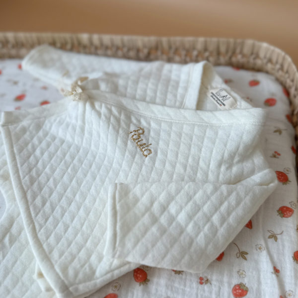 Offrez à votre bébé un premier vêtement doux, élégant et entièrement fabriqué en France avec cet adorable ensemble de naissance en coton matelassé écru. Composé d’une brassière croisée et d’un pantalon assorti, cet ensemble enveloppe bébé de confort dès ses premiers jours.
